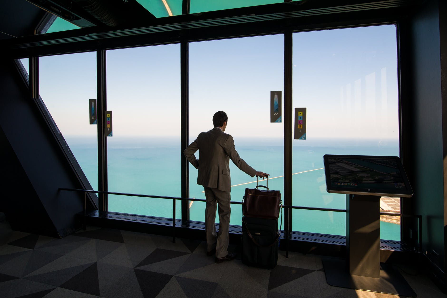 man standing with a luggage and looking at the view of an ocean